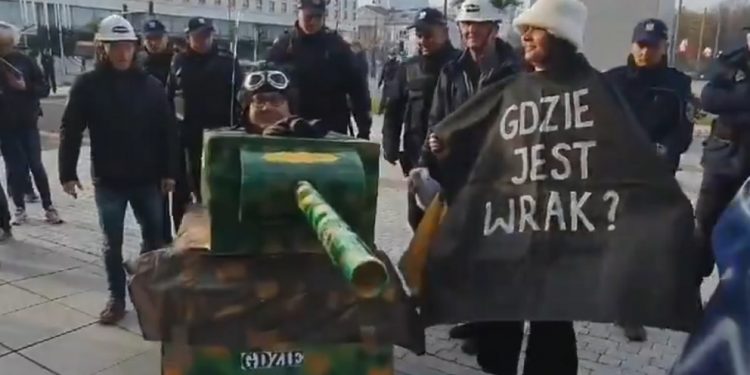 Aktywiści „Lotnej Brygady Opozycji” przed pomnikiem smoleńskim. Jeden z nich przebrał się za czołg